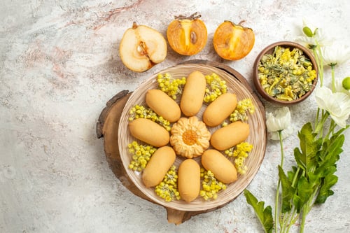 Preview: a plate of cookies on wooden platter and a bowl of herbs and half-pear and palm and flowers
