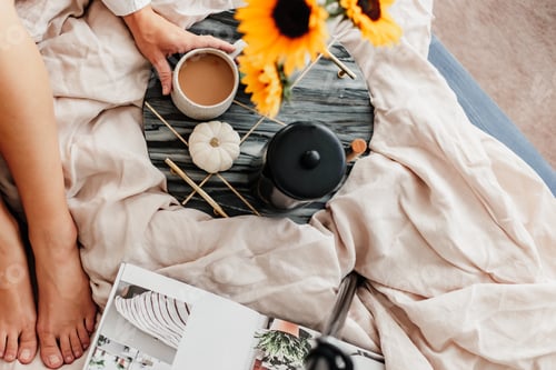 Preview: Woman is enjoying coffee in the bed. Working on the laptop.