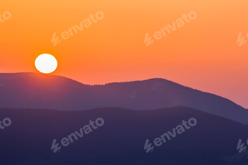 Preview: Fantastic wide panorama view of big bright white sun in dramatic orange sky over dark purple