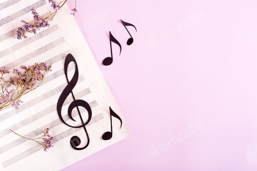 Preview: Paper musical clef and paper notes on a sheet of music and dry flowers. Top view.