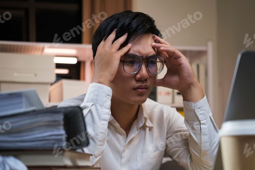 Preview: Young tired staff businessman using desktop computer having overwork project overnight in office.