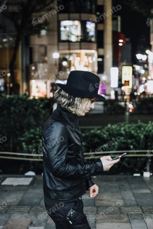 Preview: Adult Wearing Black Hat on Urban Sidewalk at Night