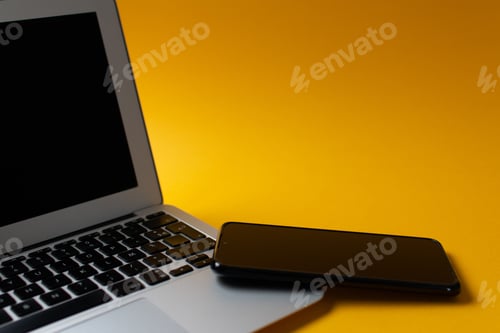 Preview: Top view of a laptop and cellphone on a yellow background