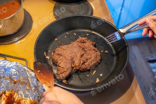 Preview: Chef frying beef steak with garlic on skillet