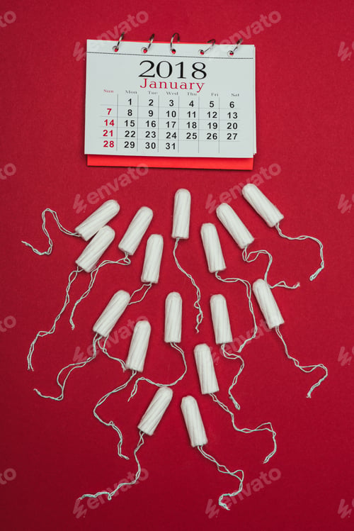 Preview: top view of arranged menstrual tampons and calendar isolated on red