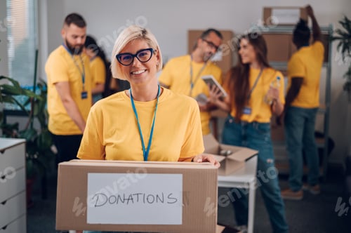 Preview: Portrait of a volunteer holding cardboard box with his colleagues in the background