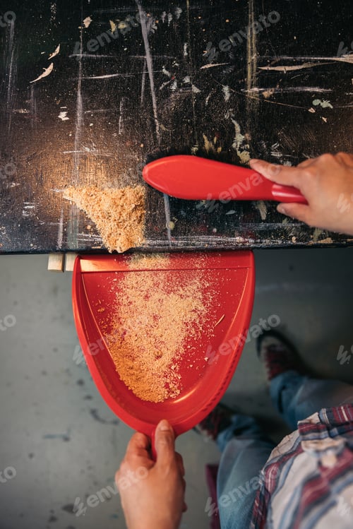 Preview: Top view female carpenter in carpentry workshop is sweeping sawdust, with a brush for dust cleaning