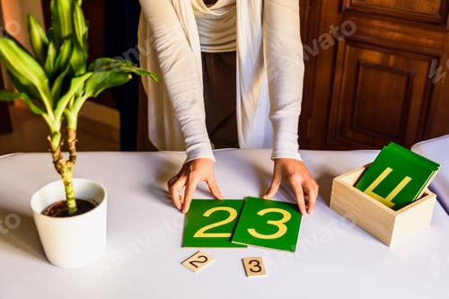 Preview: Hands of a montessori teacher guide presenting how to make sums.
