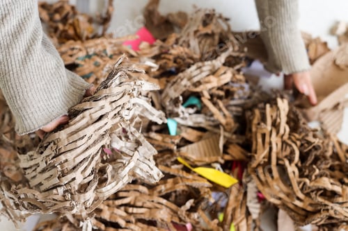 Preview: Close Up Of Hands Sifting Through Brown Corrugated Paper And Colorful Scraps