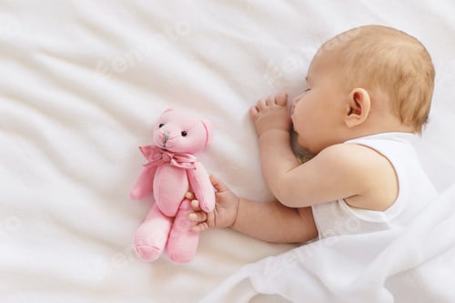 Preview: Baby sleeps with a teddy bear on a white background. Selective focus.