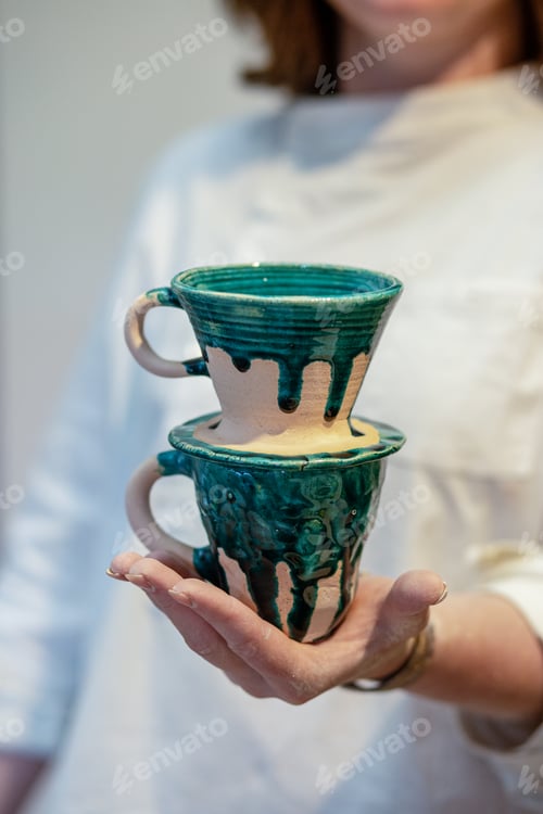 Preview: Woman holding new cups in pottery workshop. Close up. DIY and hobby concept.