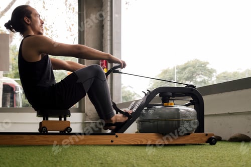 Preview: sporty man training with a water rowing machine