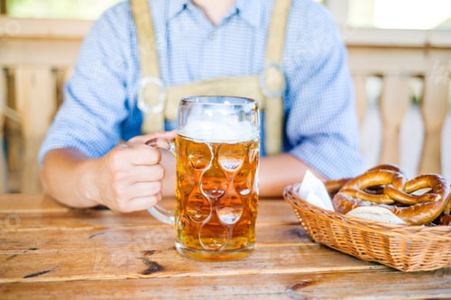 Preview: Man in traditional bavarian clothes with beer and pretzels