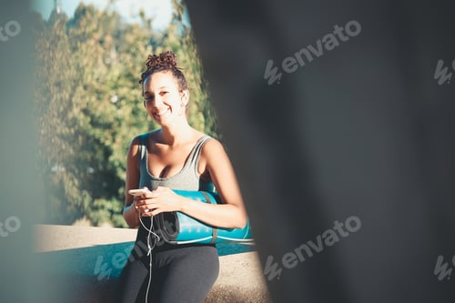 Preview: Woman with Yoga Mat and Cellphone in Park