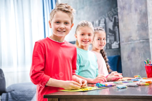 Preview: Schoolchildren playing with colorful plasticine and looking at camera