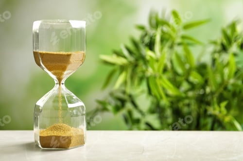 Preview: Hourglass with flowing sand on table against blurred background. Time management