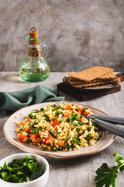 Preview: Tabbouleh salad with bulgur, tomato and parsley on a plate on the table vertical view