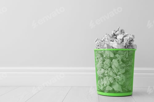 Preview: Metal bin and crumpled paper against light wall, space for text