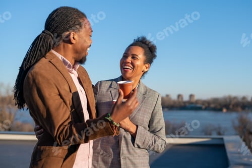 Preview: Mid-adult multiethnic business executives enjoy a sunny coffee break on top an office building
