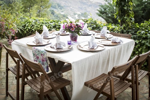 Preview: Table full of plates and a flower vase on a beautiful balcony with an amazing view