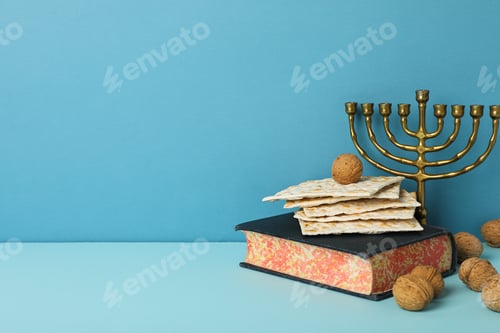 Preview: Matzo, nuts, hanukkiah and Torah on blue background, space for text