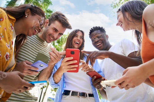 Preview: Low angle of a group of young teenagers holding cell phones. Surprised faces looking at the screen