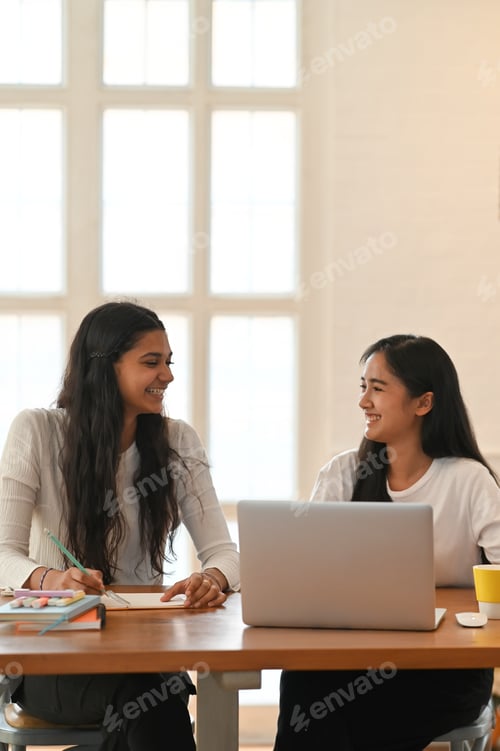 Preview: University students are sitting together in front of a computer laptop at the working desk.