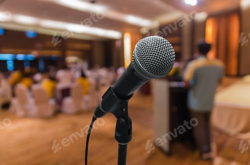 Preview: Microphone over the Abstract blurred photo of conference hall or seminar room