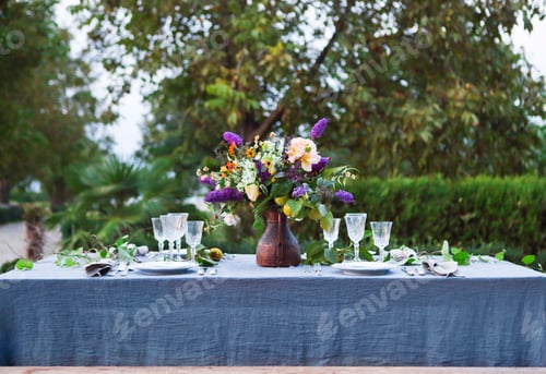 Preview: Bouquet of pink, violet and yellow flowers on a table set for dinner