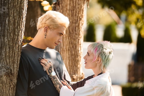 Preview: Young couple shares a tender moment under the shade of trees in a serene park setting