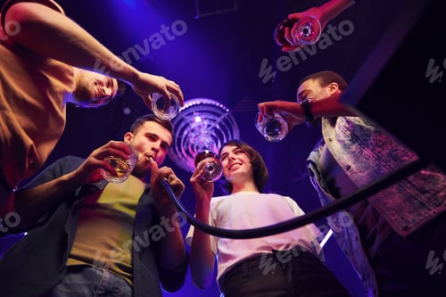 Preview: Holding glasses in hands. Group of friends having fun in the night club together