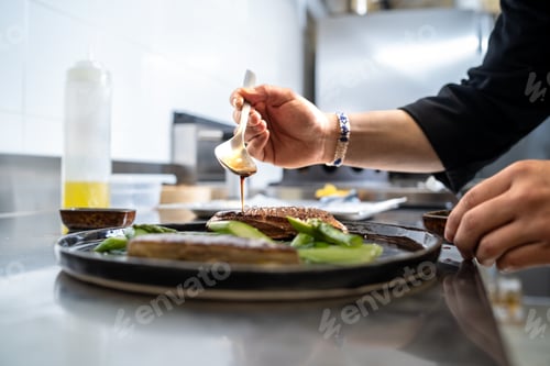 Preview: Chef plating grilled fish with soy sauce and fresh vegetables in kitchen