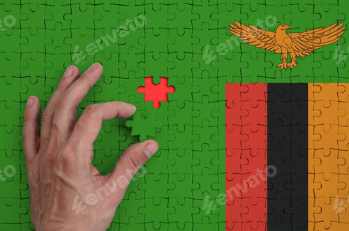 Preview: Zambia flag is depicted on a puzzle, which the man's hand completes to fold.