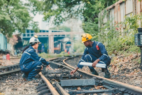 Preview: Engineer in safety gear inspects railway track for wear and alignment, ensuring safety standards.