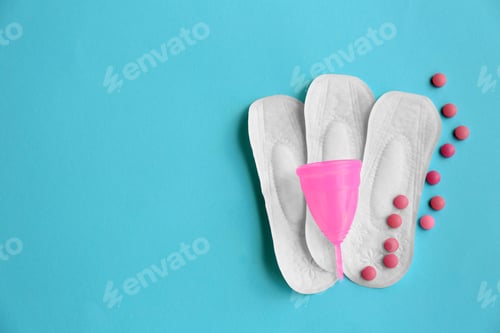 Preview: Flat lay composition with menstrual pads, cup and pills on color background. Gynecological care