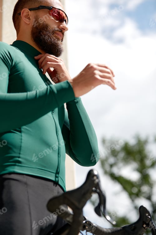Preview: Strong Male cyclist in sportswear, glasses and protective helmet walking with his bike in the forest