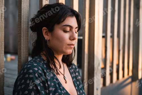 Preview: Young girl in profile leaning on a wooden fence