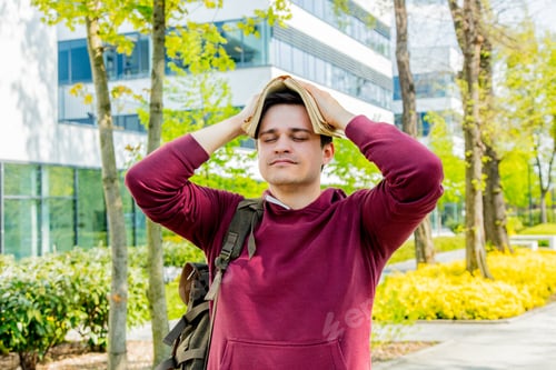 Preview: Young upset student with book on head stay near modern building of University