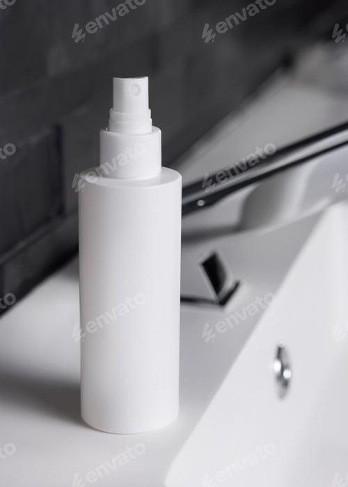 Preview: White spray bottle near modern faucet on basin in dark grey bathroom close up, cosmetic mockup
