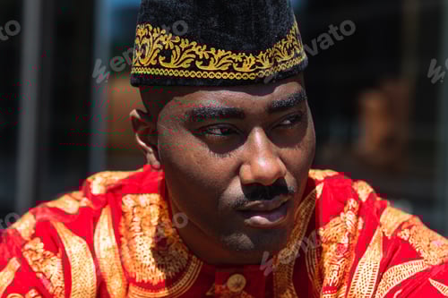 Preview: Thoughtful black man in traditional clothes and headdress near building