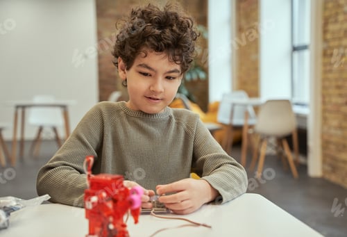 Preview: Learn how it works. Lovely little boy sitting at the table, checking technical toy full
