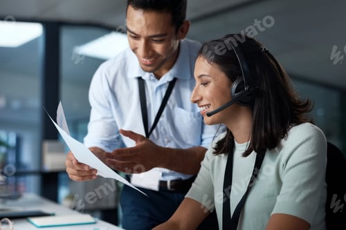 Preview: Shot of a young man and woman reading a document while working in a call centre