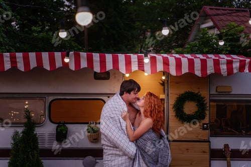 Preview: A young couple of happy lovers wrapped themselves in a white blanket by the trailer truck