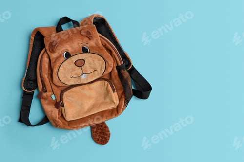 Preview: Fluffy backpack shape of beaver with school supplies on blue background. Top view