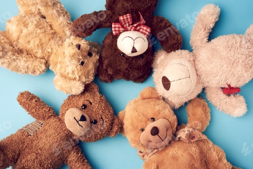 Preview: Various teddy bears lie on a blue background head to head and look up