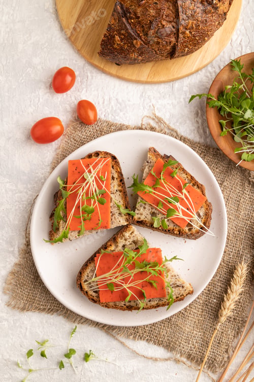 Preview: Grain bread sandwiches with red tomato cheese and microgreen on gray, top view, close up.