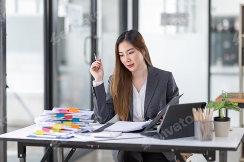 Preview: Portrait of tired young business Asian woman work with documents tax laptop computer in office. Sad,