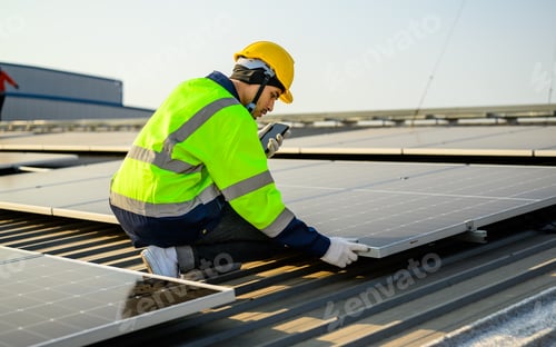 Preview: Engineer with helmet working at solar cell power plant with sunset in evening