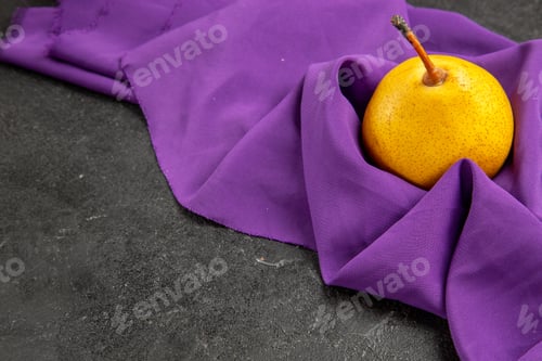 Preview: side close-up view pear on the tablecloth yellow pear on the purple tablecloth on the dark table