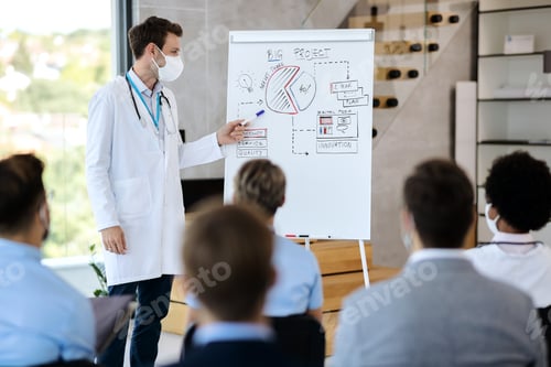 Preview: Doctor with face mask giving presentation to group of colleagues and business people in board room.